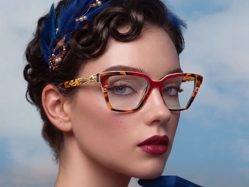 A woman wearing patterned CocoSong frames with a feathered headpiece