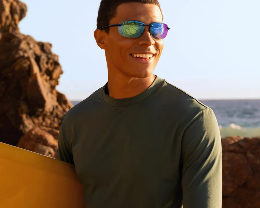 A man in mirrored sunglasses outdoors beside a rock face