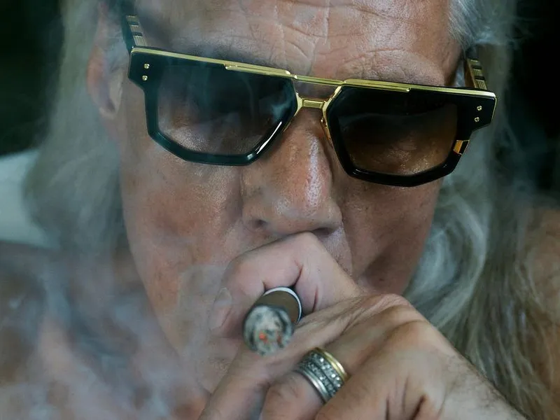 A person wearing angular DITA sunglasses with a gold browbar