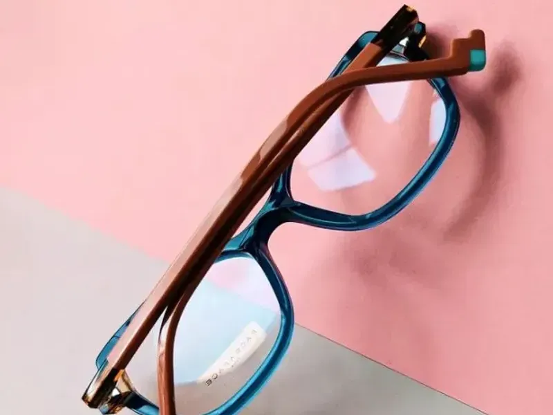 A blue and tan acetate frame standing against a pink ground