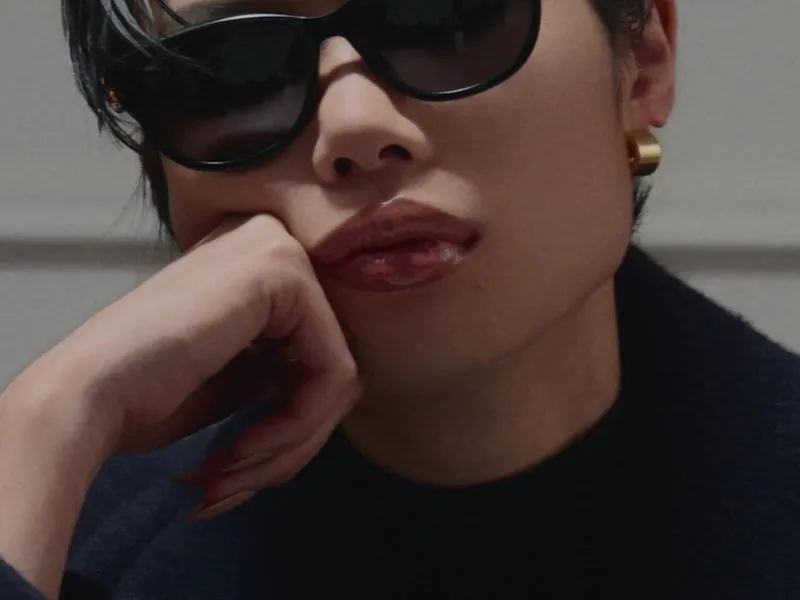 A close portrait of a woman wearing dark Gucci sunglasses