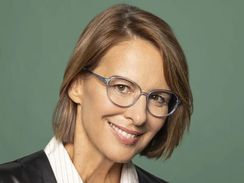 A woman wearing slim Stepper spectacles against a green backdrop