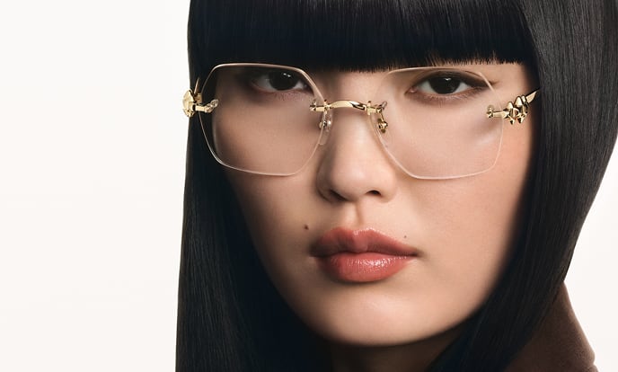 A woman wearing rimless Cartier optical frames with gold panther detailing