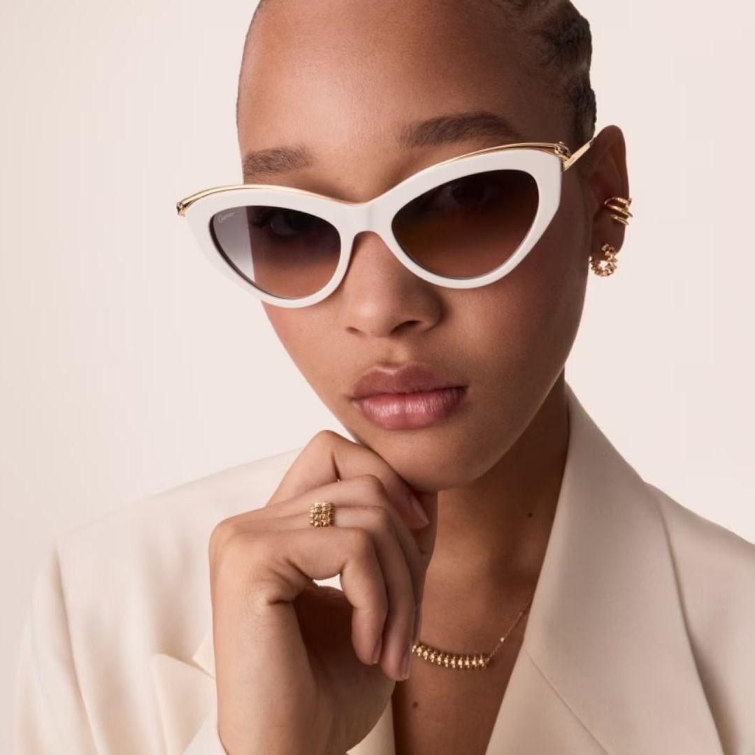 A woman wearing white Panthère de Cartier cat-eye sunglasses with a gold panther at the hinge