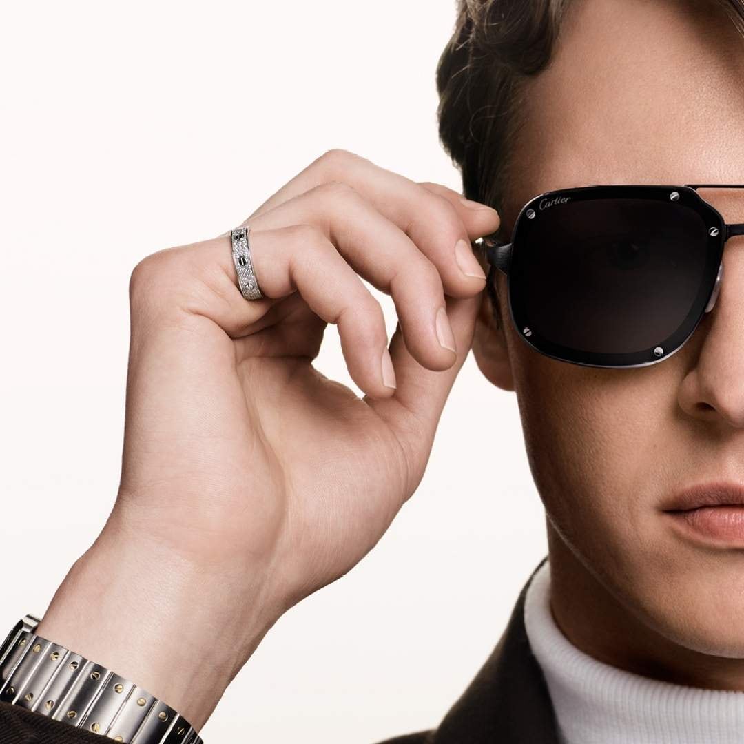 A man wearing Santos de Cartier sunglasses, the screw details visible on the rim